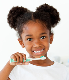 Young girl smiling at camera brushing white teeth